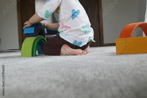 Child playing with wooden rainbow blocks with negative space