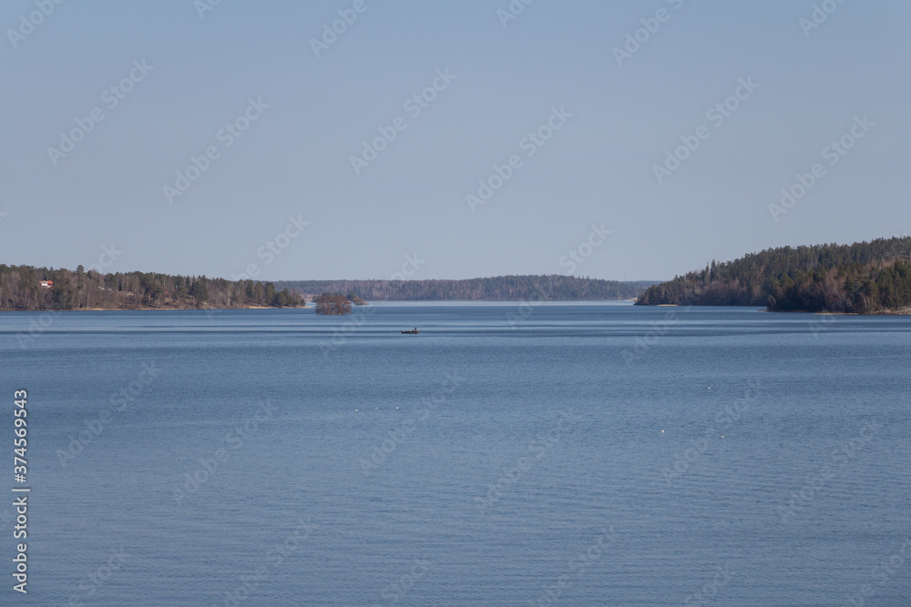 Peacefull landscape with boat in the lake Malaren and forest on background, Sweden.
