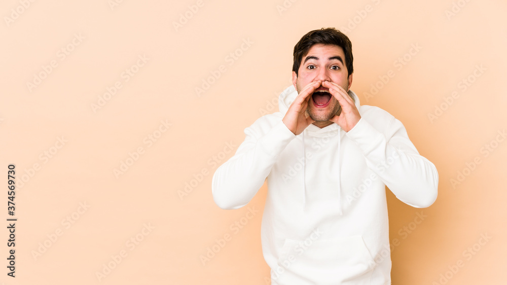 Young man isolated on beige background shouting excited to front. Young man isolated on beige background shouting excited to front.
