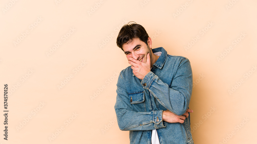 Young man isolated on beige background laughing happy, carefree, natural emotion.