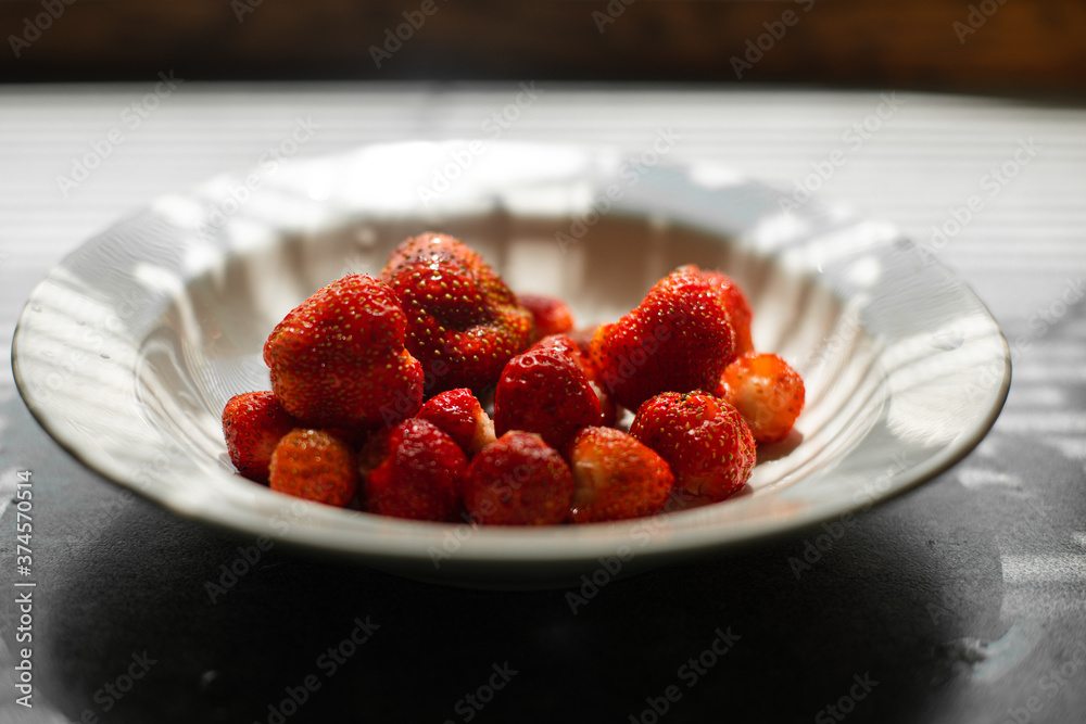 Picture of juicy fresh ripe red strawberries in a white ceramic plate with light background Picture of juicy fresh ripe red strawberries in a white ceramic plate with light background