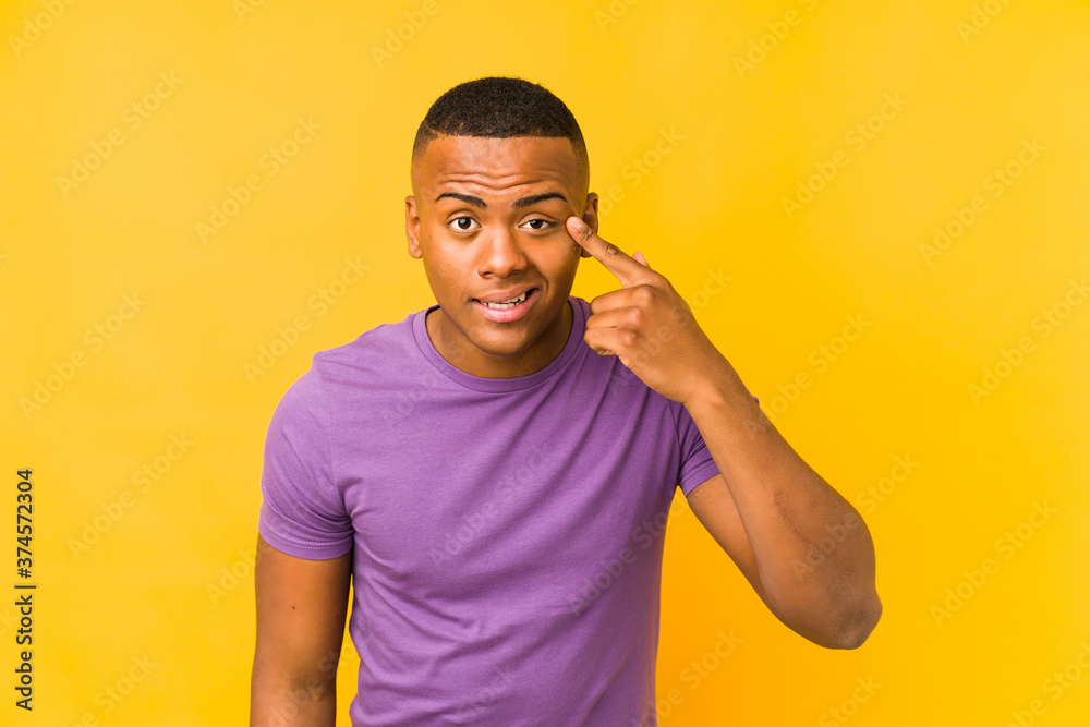 Young latin man isolated on yellow background showing a disappointment gesture with forefinger. Young latin man isolated on yellow background showing a disappointment gesture with forefinger.