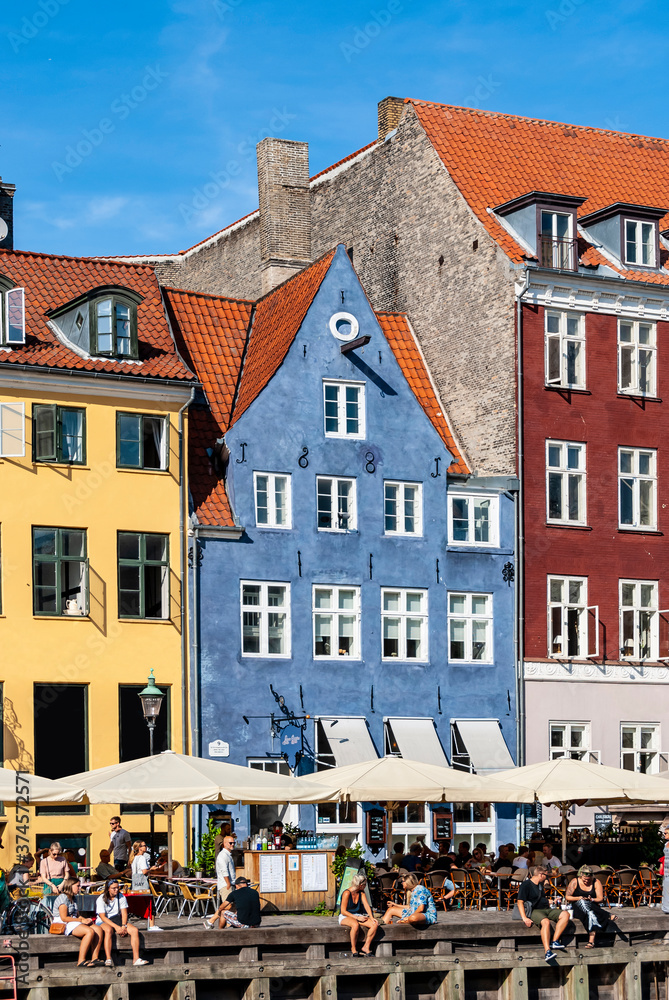 Fototapeta premium Detail of the touristic Nyhavn pier with people having relax, colorful buildings and boats in Old Town of Copenhagen, Denmark