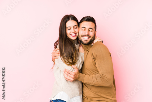 Young caucasian couple isolated hugs, smiling carefree and happy.