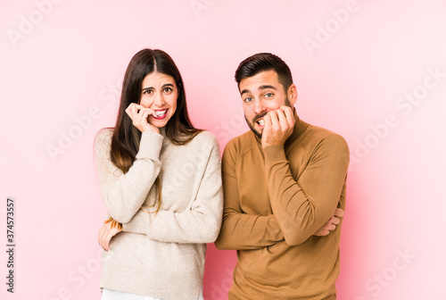 Young caucasian couple isolated biting fingernails, nervous and very anxious.