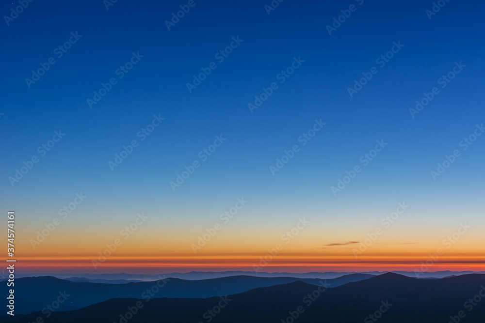 The first or last rays of the sun on a mountain pass. Morning and evening in nature. Colorful sunset and sunrise over the mountain hills. Carpathians in summer and autumn.