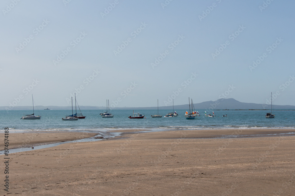 Obraz premium North Shore, New Zealand - November 25 2019: the view of boats at Waiake beach and Rangitoto island on background on November 25 2019 in Auckland, New Zealand.