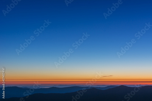 The first or last rays of the sun on a mountain pass. Morning and evening in nature. Colorful sunset and sunrise over the mountain hills. Carpathians in summer and autumn.