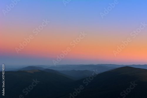 The first or last rays of the sun on a mountain pass. Morning and evening in nature. Colorful sunset and sunrise over the mountain hills. Carpathians in summer and autumn.