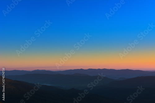 The first or last rays of the sun on a mountain pass. Morning and evening in nature. Colorful sunset and sunrise over the mountain hills. Carpathians in summer and autumn.