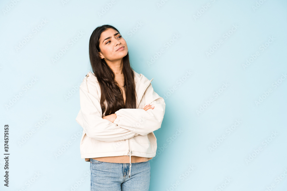 Young indian woman on blue background dreaming of achieving goals and purposes Young indian woman on blue background dreaming of achieving goals and purposes