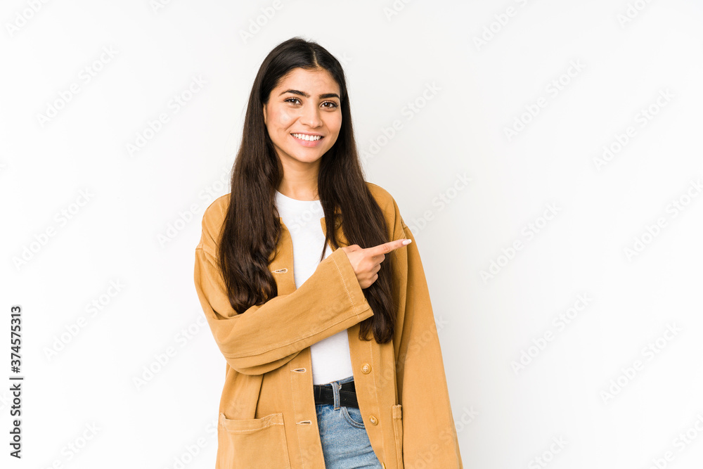 Young indian woman isolated on purple background smiling and pointing aside, showing something at blank space. Young indian woman isolated on purple background smiling and pointing aside, showing something at blank space.