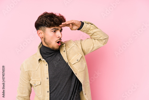 Young arabian man posing in a background isolated looking far away keeping hand on forehead.