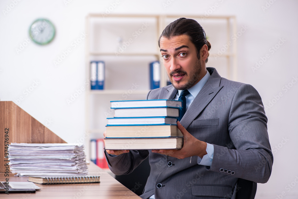 Young male businessman reading books at workplace Young male businessman reading books at workplace