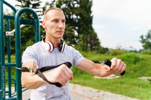 Adult caucasian man training outdoor in summer day - Male athlete using resistance band tubes in his daily workout routine - Real people health and fitness concept