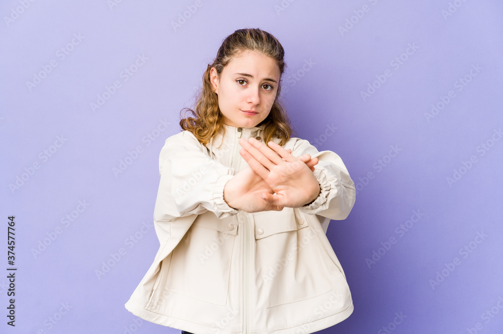 Young caucasian woman on purple background standing with outstretched hand showing stop sign, preventing you.