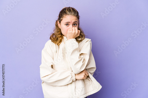 Young caucasian woman on purple background biting fingernails, nervous and very anxious.