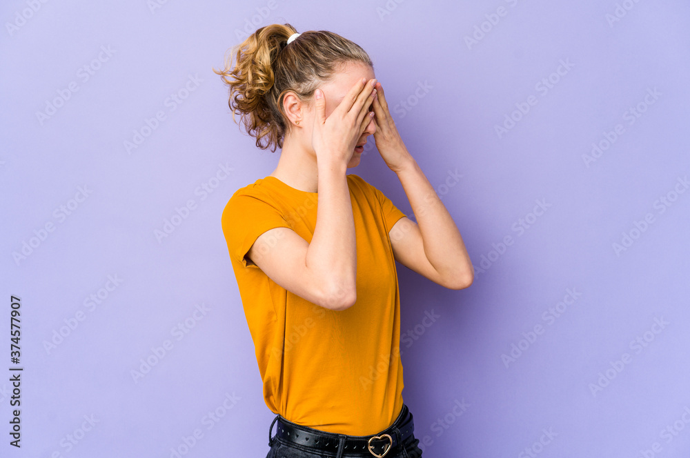 Young caucasian woman on purple background afraid covering eyes with hands. Young caucasian woman on purple background afraid covering eyes with hands.