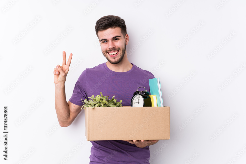 Young caucasian man moving a new home isolated joyful and carefree showing a peace symbol with fingers. Young caucasian man moving a new home isolated joyful and carefree showing a peace symbol with fingers.