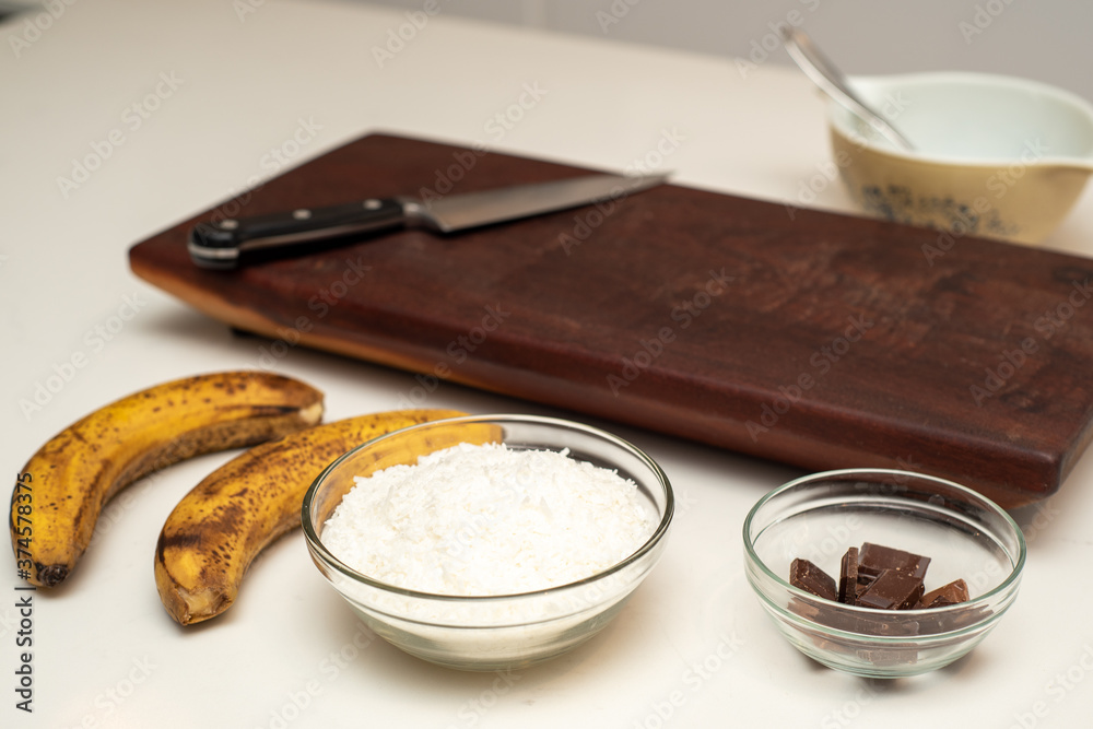 Coconut and banana cookies preparation drizzled with melted chocolate. Ingredients displayed. Coconut and banana cookies preparation drizzled with melted chocolate. Ingredients displayed.