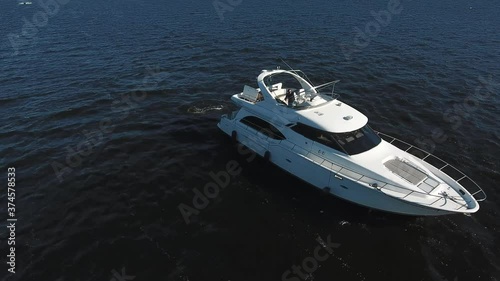 The man drive the yacht from the upper deck. View from a quadcopter