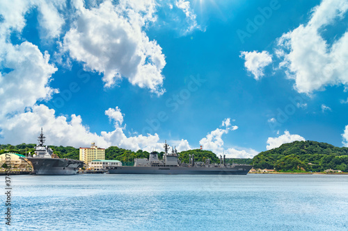 yokosuka, japan - july 19 2020: Wide angle view of the japanese  Replenishment oiler JS Masyu AOE-425 and the Destroyer JS Izumo DDH-183 berthed in the Yokosuka naval port under the summer blue sky. photo