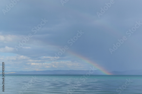 Rainbow over the lake. Baikal. Dry bay. Beautiful blue sky background. Water mirrors water