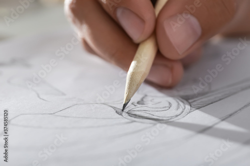 Man drawing portrait with pencil in notepad, closeup