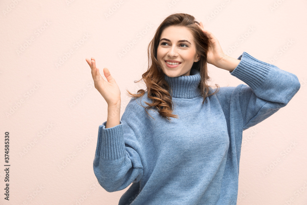 Beautiful young woman wearing warm blue sweater on light pink background Beautiful young woman wearing warm blue sweater on light pink background