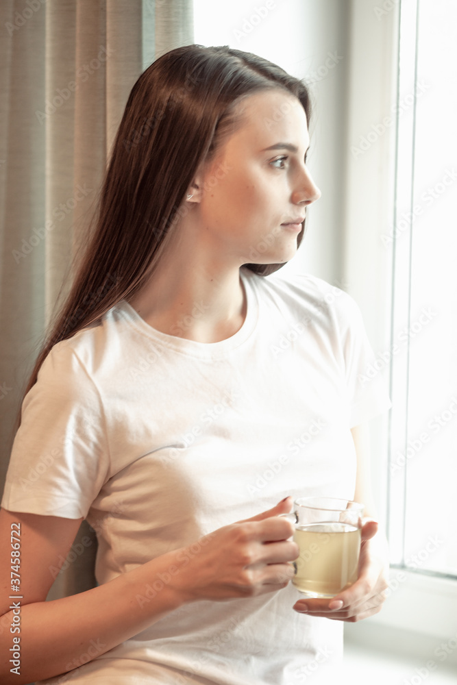 Beautiful woman drinking morning tea behind window Beautiful woman drinking morning tea behind window