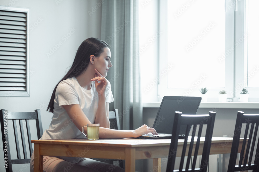 Girl working on computer laptop in light room