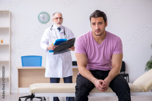 Old doctor radiologist examining young male patient © Elnur