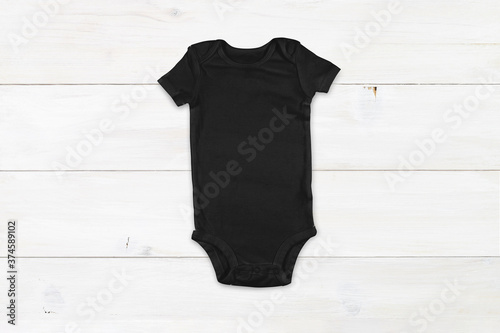 Black baby onesie mockup on white wood background photo