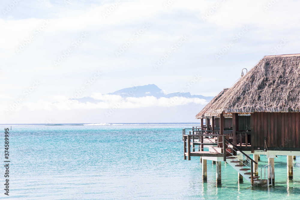 Thatched roof over-water bungalows on a tropical island in the South Pacific ocean