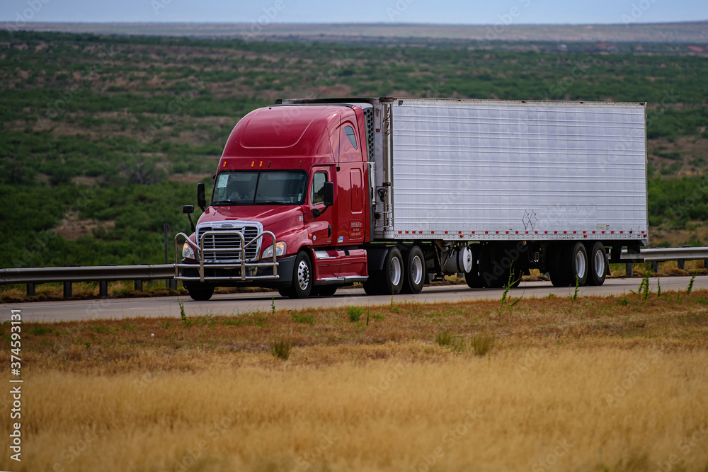 Arizona, USA - May, 2020: Trucks on American roads. Delivery. A big red truck and a trailer with space for text on the countryside road in motion against the mountains.