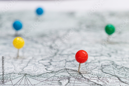 Close up white and black map with colorful stickpins pinpointing a location