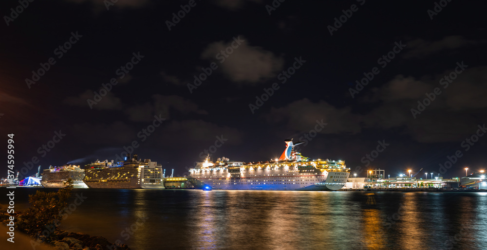 Miami, Florida, USA - MAY, 2020: Big white cruise ship docked at the port of Miami at night. Large luxury cruise ship on sea water at night with illuminated light docked at port of Miami.