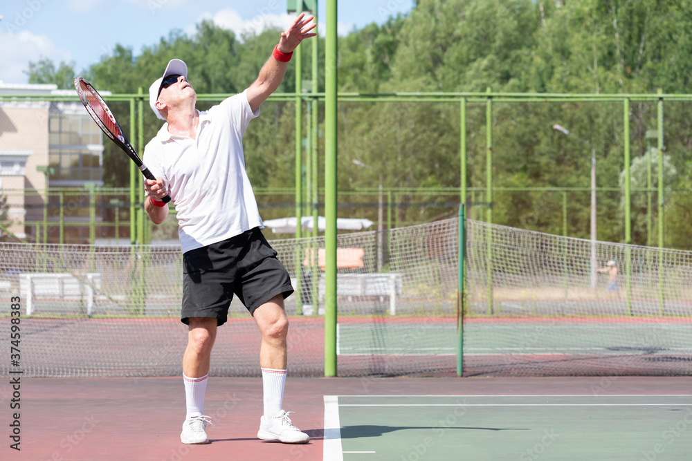 An elderly man plays tennis on an outdoor court