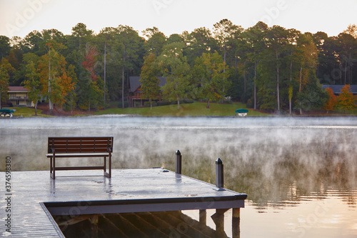 Fototapeta Naklejka Na Ścianę i Meble -  Bench on the dock of the bay on a Georgia lake with steam rising from the water