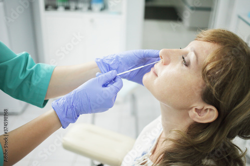 A nurse wearing a medical mask takes a swab from a patient's nose.