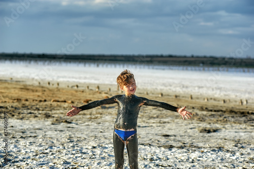 Happy little boy takes a mud bath at the mud-bath resort photo