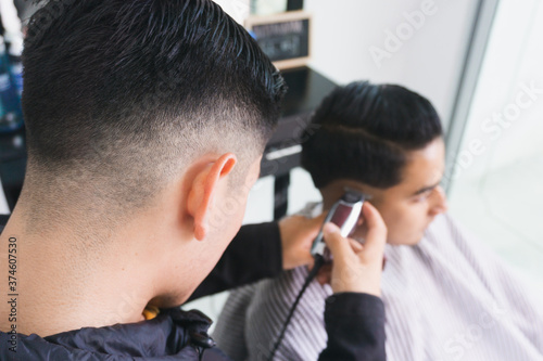 young barber cutting hair in barbershop