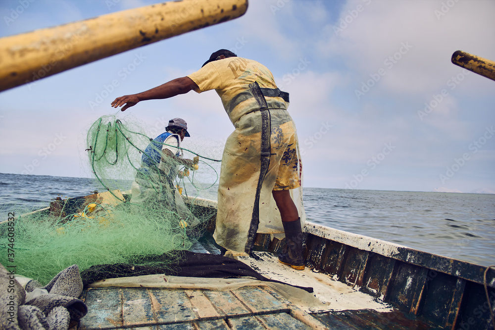 Pescadores preparando las redes de pesca en un bote en medio del océano  pacifico Photos