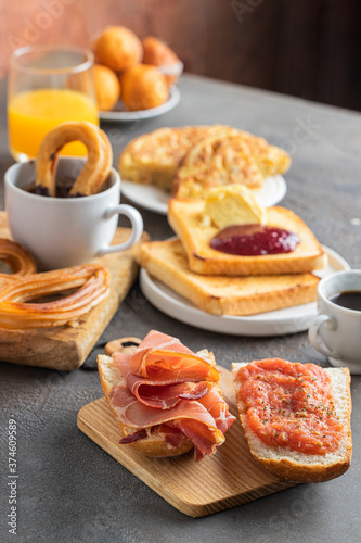 Spanish breakfast, tortilla, bruschetta with jamon (cured ham) and tomatoes, churros with chocolate, crusty  french toast with butter and jam ,coffee and orange juice.