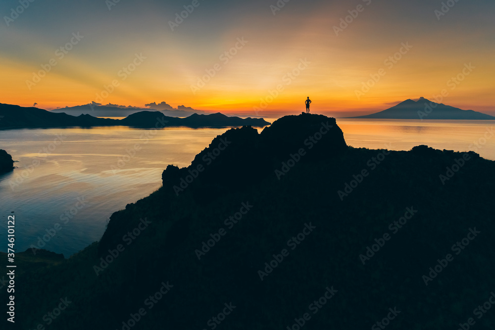 Fototapeta premium Padar island.Wild Indonesia. Flores. tropical paradise. Labuan Bajo. drone shooting. Wild beaches, aerial view. boat trip safari. one men watching the sunset or sunrise on the hill. Vulcano view
