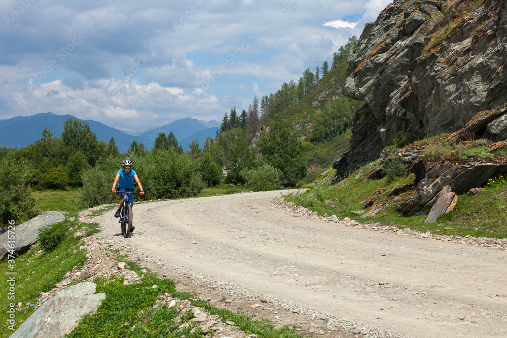 The young man rides a bicycle in the mountains.