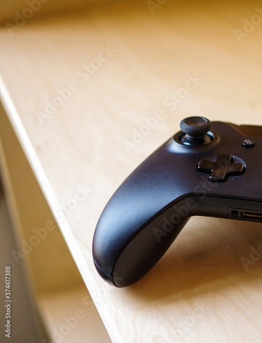 Black wireless game controller on wooden table