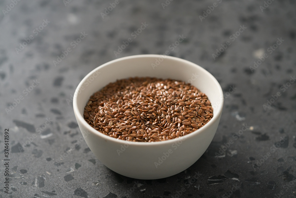 Flax seeds in white bowl on terrazzo surface with copy space