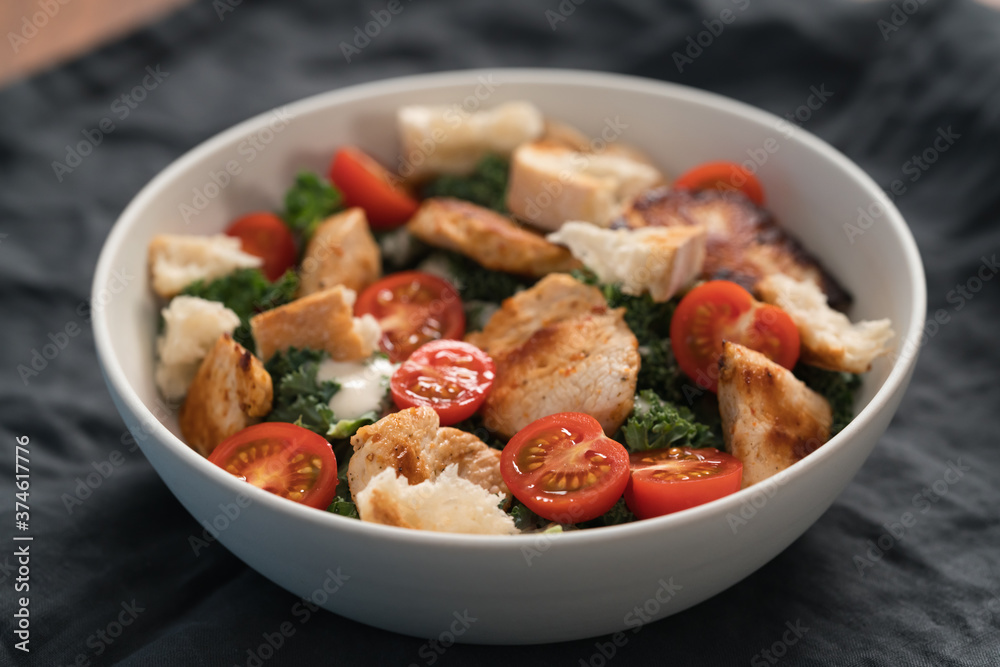 Caesar salad alternative with kale and turkey in white bowl Caesar salad alternative with kale and turkey in white bowl