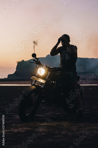 Male model on a custom bike during sunset in the beach © Younes